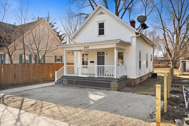 view of front of property featuring covered porch, driveway, a chimney, and fence