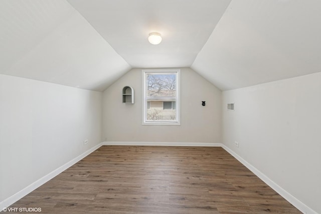 bonus room with lofted ceiling, wood finished floors, baseboards, and visible vents