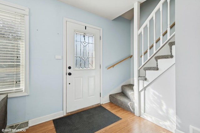 foyer entrance featuring stairs, wood finished floors, visible vents, and baseboards