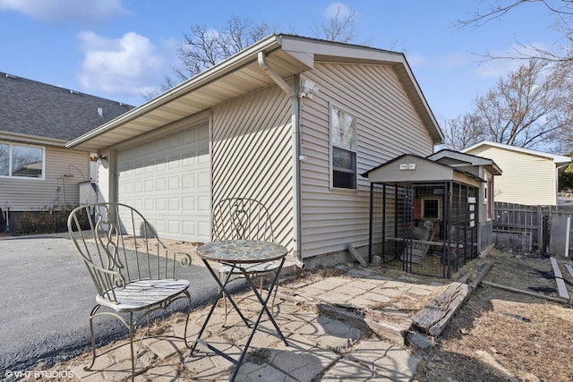 rear view of house with a garage, driveway, and fence