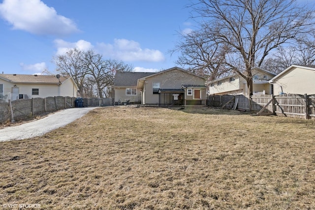 back of house with a lawn and a fenced backyard