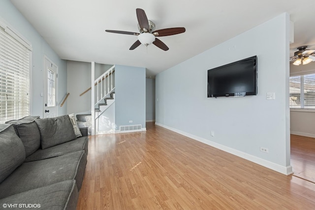 living room with stairway, baseboards, visible vents, and wood finished floors