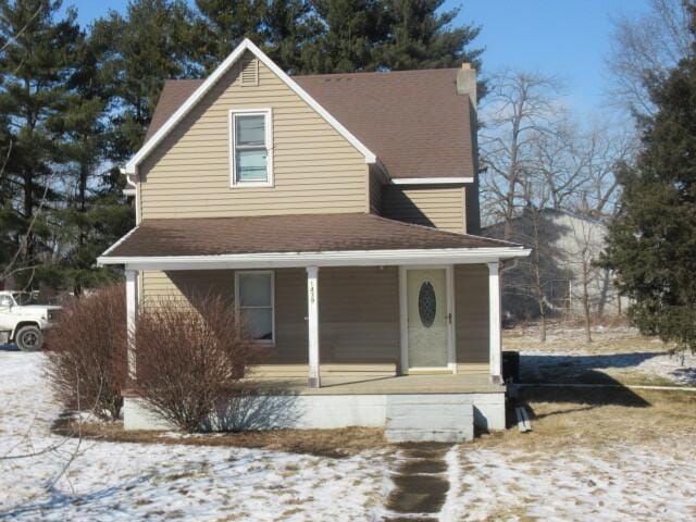 view of front of property featuring covered porch, a shingled roof, and a chimney