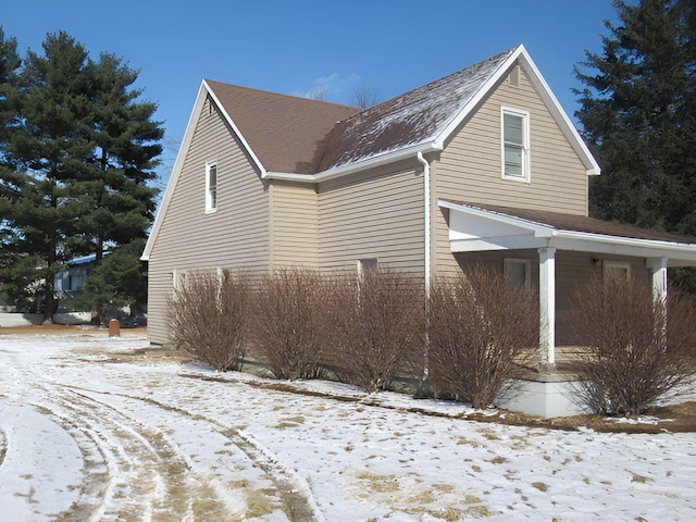 view of snowy exterior featuring roof with shingles