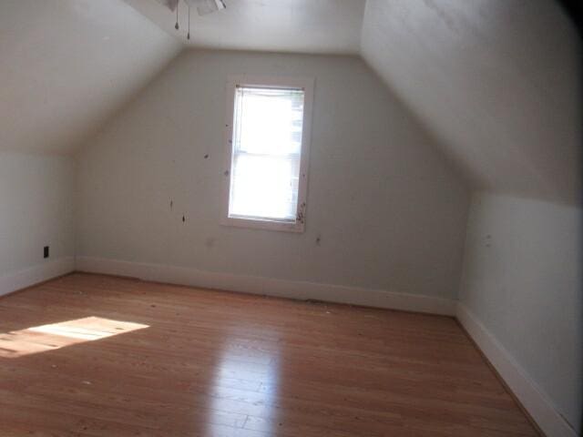 bonus room with light wood-type flooring, baseboards, and vaulted ceiling