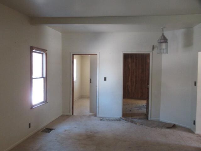 unfurnished bedroom with light colored carpet, visible vents, and beamed ceiling