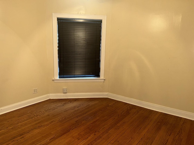 spare room with dark wood-type flooring and baseboards