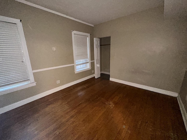 unfurnished room with dark wood finished floors and baseboards