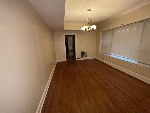 unfurnished dining area featuring dark wood-style flooring, visible vents, baseboards, and an inviting chandelier