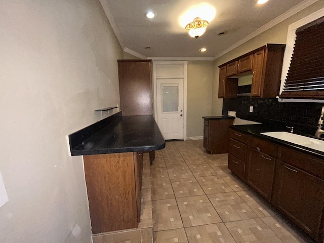 kitchen with tasteful backsplash, dark countertops, a sink, and ornamental molding