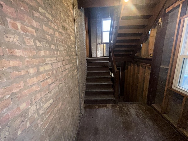 staircase featuring brick wall