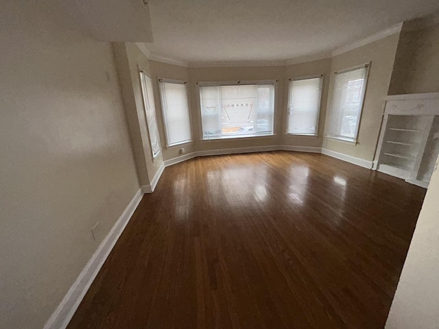 unfurnished living room featuring a premium fireplace, baseboards, wood finished floors, and ornamental molding