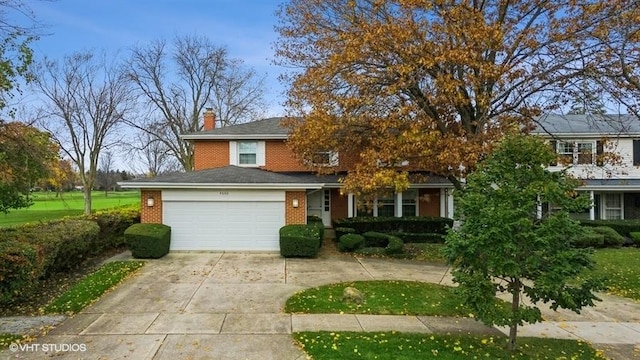 view of front facade featuring concrete driveway, a garage, brick siding, and a chimney