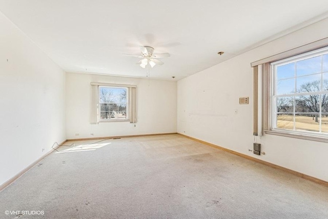 unfurnished room with light colored carpet, a ceiling fan, and baseboards