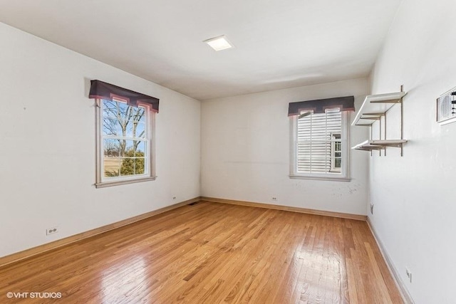 empty room with baseboards, a healthy amount of sunlight, and light wood-style flooring