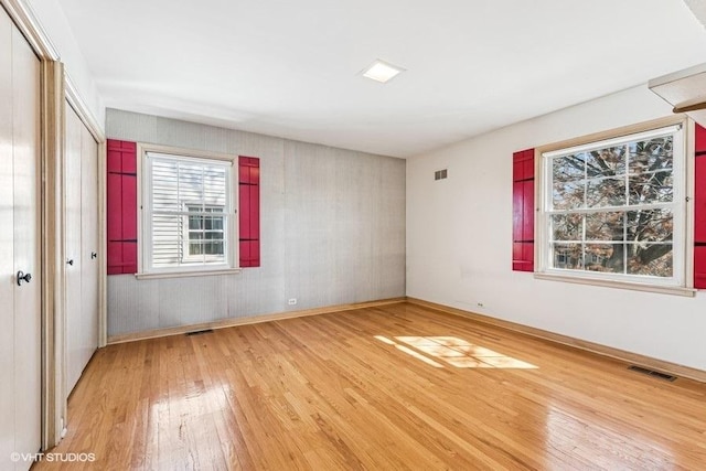 spare room with hardwood / wood-style floors and visible vents