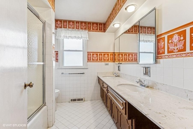 bathroom featuring visible vents, a sink, tile patterned flooring, wainscoting, and tile walls