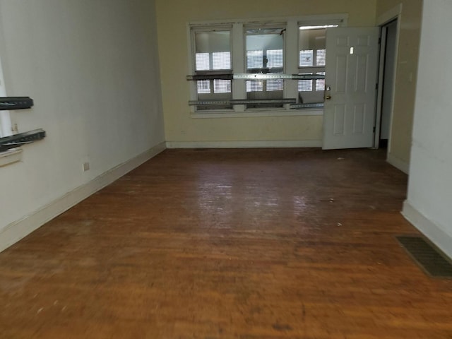 spare room featuring baseboards, visible vents, and dark wood finished floors