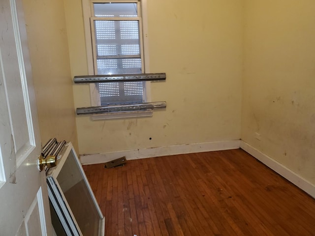 unfurnished room with baseboards and hardwood / wood-style floors