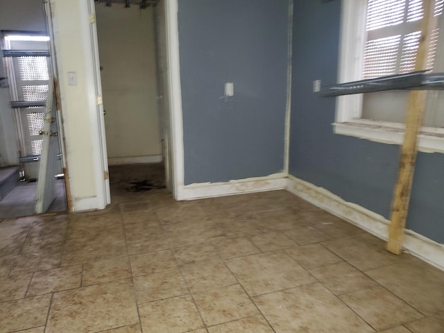 interior space featuring baseboards, a wealth of natural light, and tile patterned floors