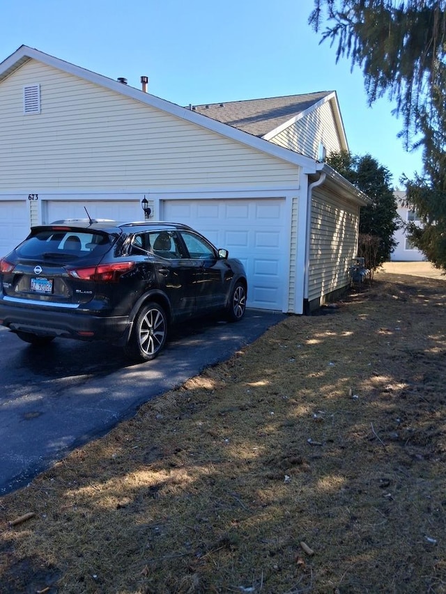 view of side of home with an attached garage and driveway