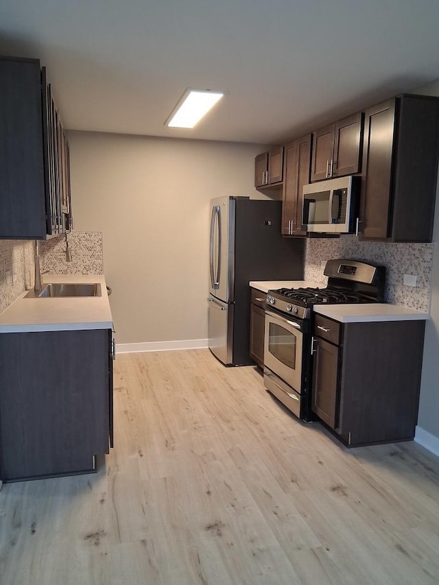 kitchen featuring decorative backsplash, light wood-style flooring, appliances with stainless steel finishes, light countertops, and a sink