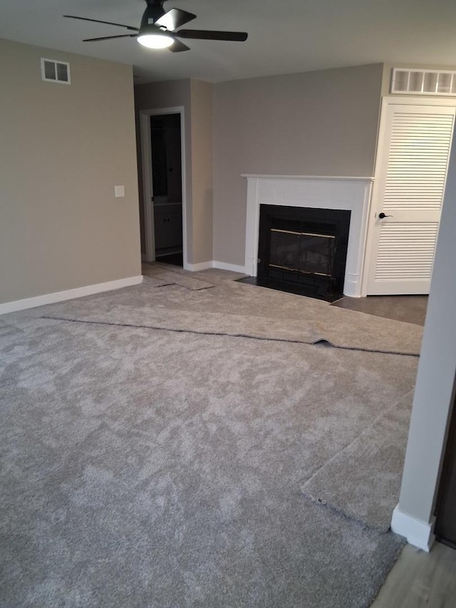 unfurnished living room with visible vents, a fireplace with flush hearth, baseboards, and a ceiling fan