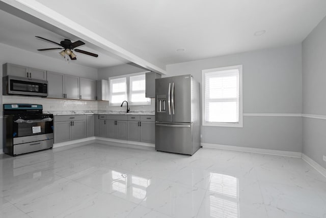 kitchen featuring a sink, baseboards, marble finish floor, appliances with stainless steel finishes, and gray cabinets