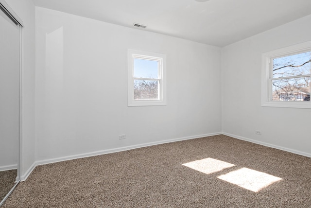 carpeted spare room with visible vents and baseboards