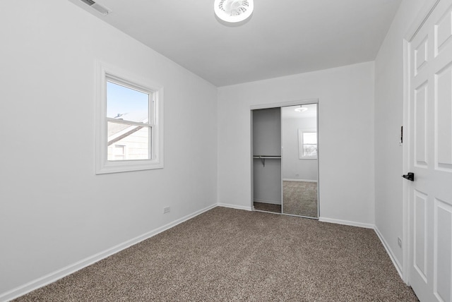 unfurnished bedroom featuring a closet, visible vents, dark carpet, and baseboards