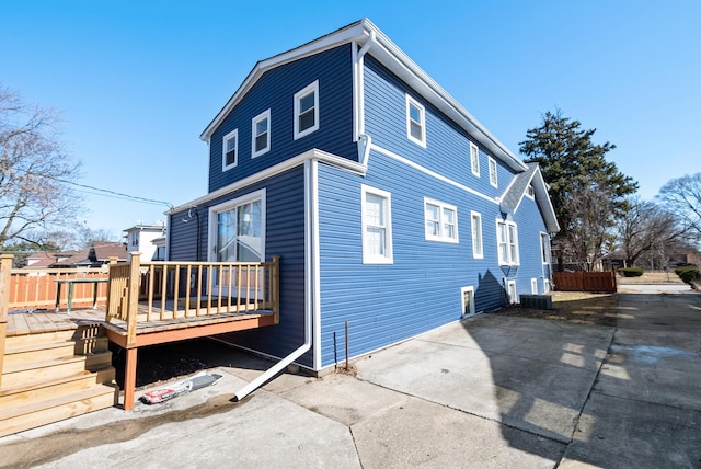 view of side of home with a deck and fence