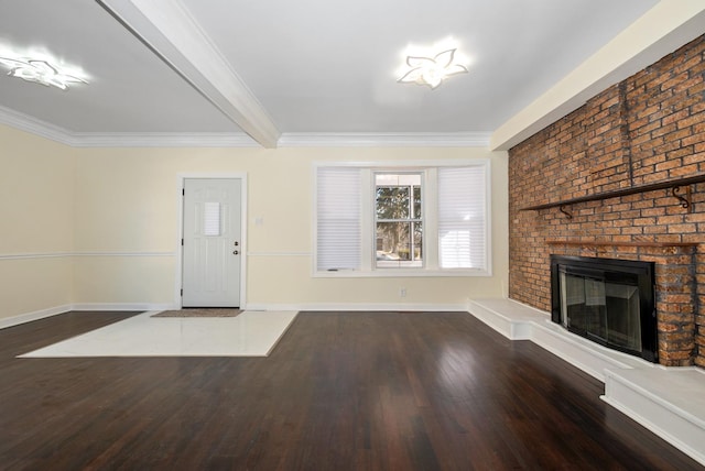 foyer entrance featuring a brick fireplace, crown molding, baseboards, and wood finished floors