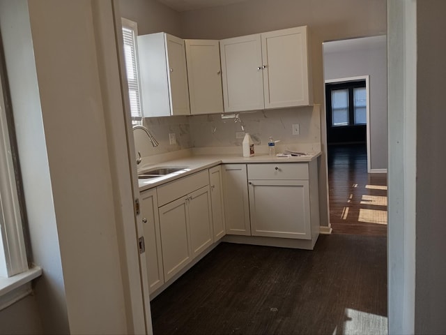 kitchen with baseboards, white cabinets, dark wood finished floors, light countertops, and a sink