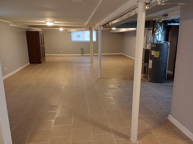 basement featuring light tile patterned floors, electric water heater, and baseboards