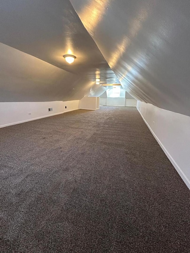 bonus room featuring lofted ceiling, a textured ceiling, baseboards, and carpet flooring