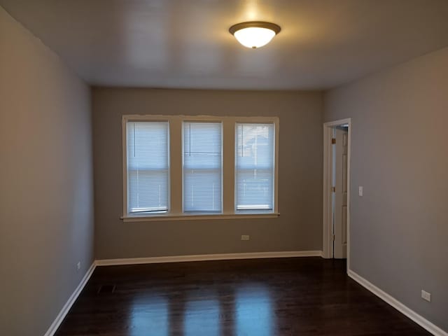 empty room featuring baseboards and dark wood-style flooring