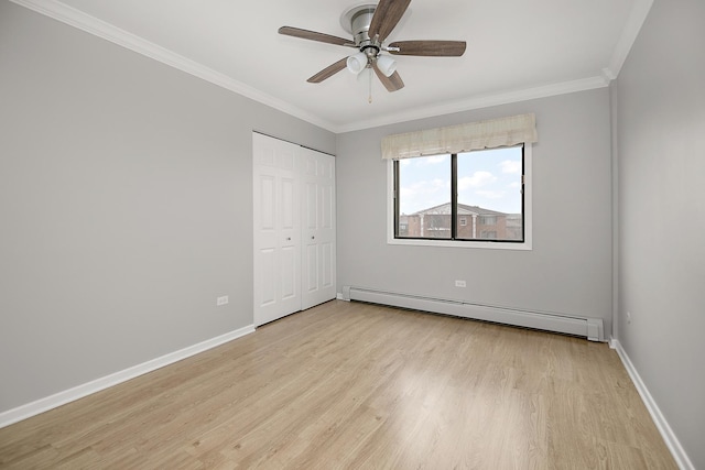 unfurnished bedroom featuring a baseboard heating unit, baseboards, light wood-type flooring, ornamental molding, and a closet