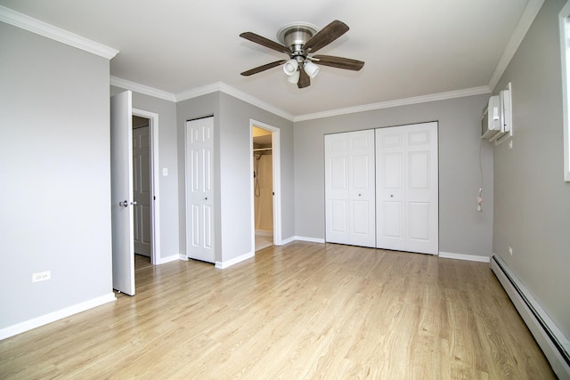 unfurnished bedroom with baseboard heating, light wood-type flooring, ornamental molding, a wall mounted AC, and baseboards