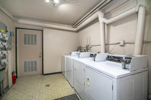 community laundry room with washer and clothes dryer, visible vents, light floors, and concrete block wall