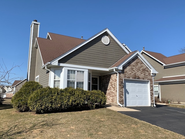 view of front of home with driveway, a front yard, a garage, brick siding, and a chimney