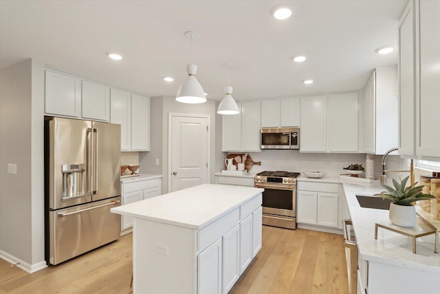 kitchen with appliances with stainless steel finishes, a center island, a sink, and light wood-style flooring