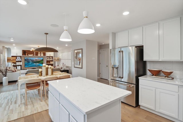 kitchen featuring light wood-type flooring, a center island, white cabinetry, and high end refrigerator