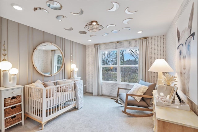 carpeted bedroom featuring a crib and wallpapered walls