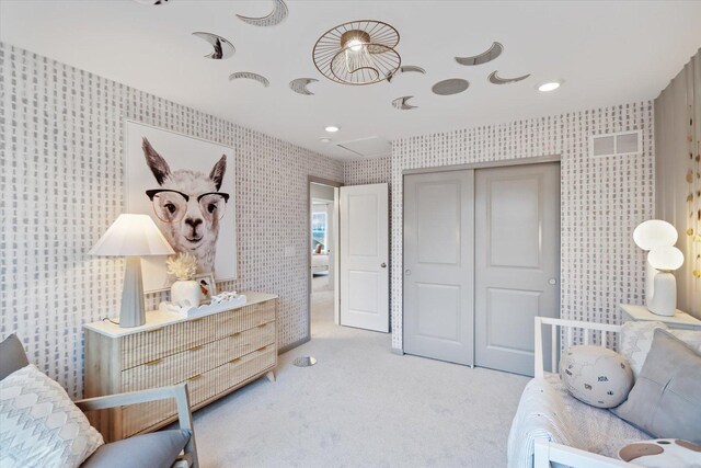 carpeted bedroom featuring a closet, visible vents, and wallpapered walls