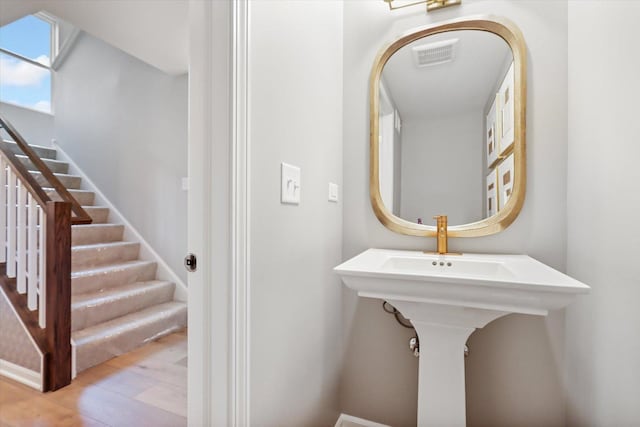 bathroom with a skylight, visible vents, and wood finished floors