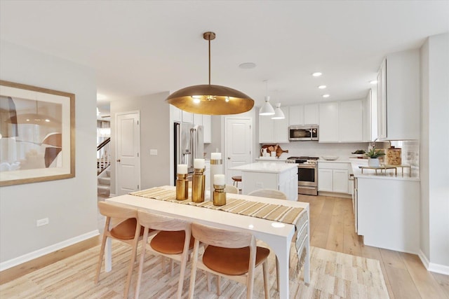 dining room featuring light wood-type flooring, recessed lighting, baseboards, and stairs