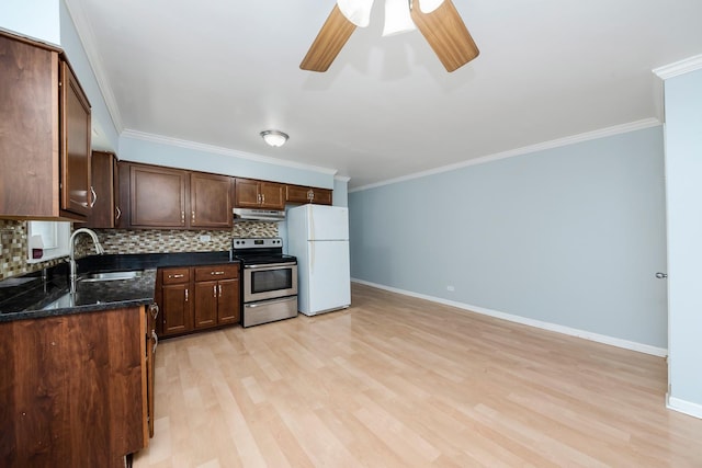 kitchen featuring electric stove, tasteful backsplash, freestanding refrigerator, and a sink