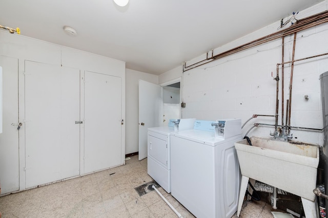 washroom featuring washing machine and dryer, light floors, concrete block wall, and a sink