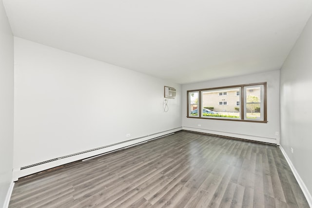 spare room with a wall mounted air conditioner, baseboards, baseboard heating, and wood finished floors