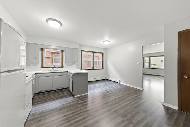 kitchen featuring dark wood finished floors, freestanding refrigerator, gray cabinetry, a sink, and light countertops